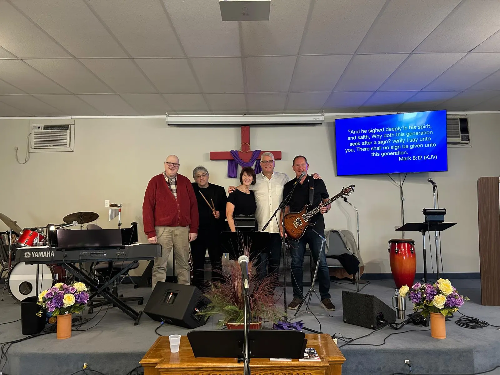 The Open Arms worship team leading music beneath the sanctuary cross
